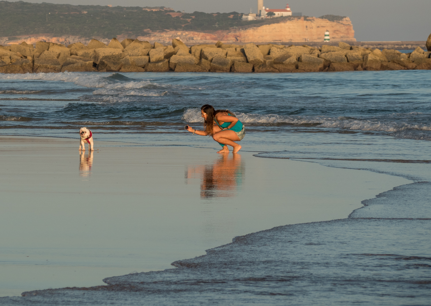 Dívka se psem na pláži pobřeží Algarve. 